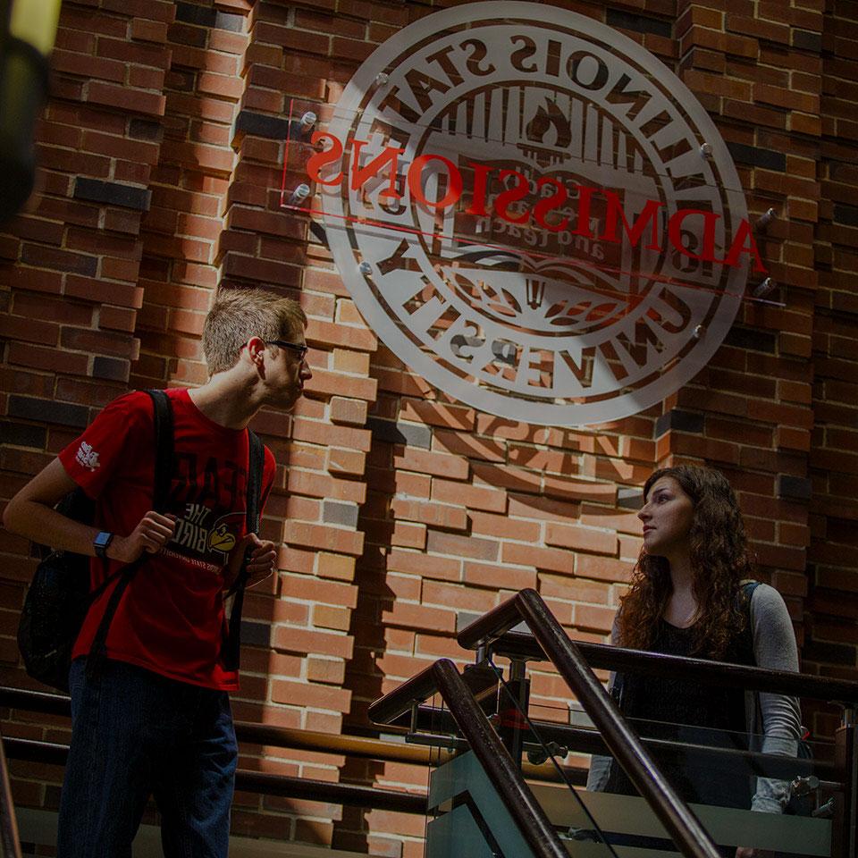 Two students standing in front of the Admssions sign.